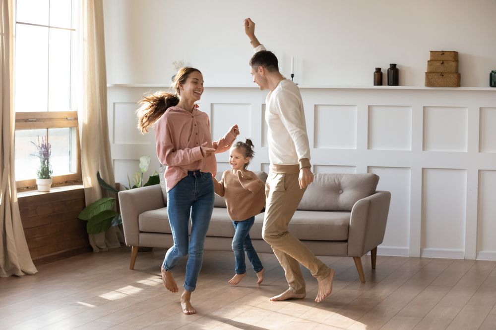 une famille de trois personnes sautant dans un salon