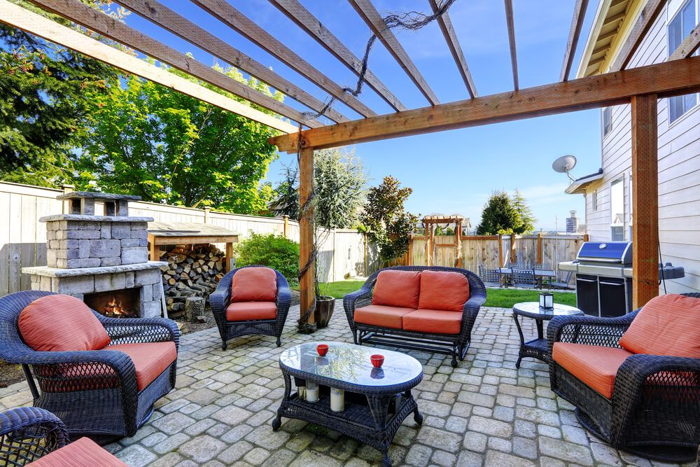 aménagement paysager : Terrasse confortable avec meubles en osier et cheminée en briques