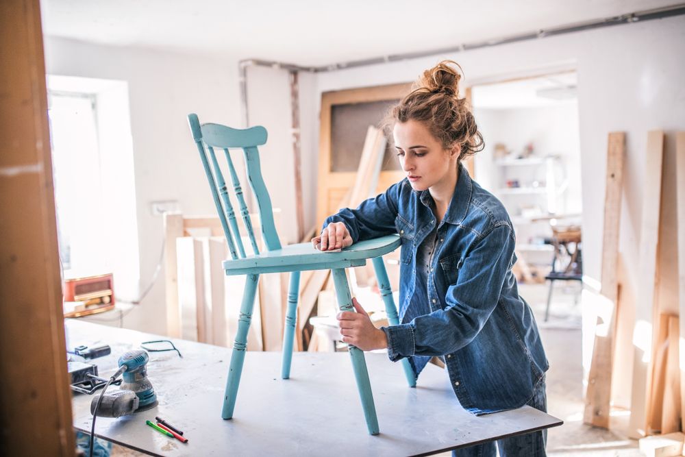 woman sanding a chair in a garage