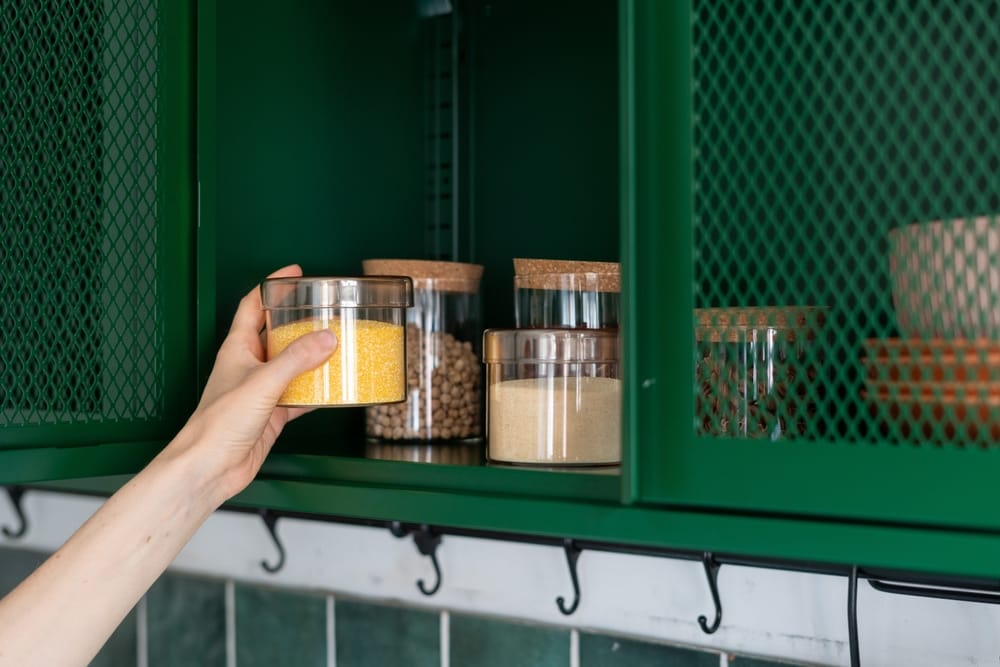 un meuble de cuisine vert avec des crochets suspendus et des boîtes en plastique