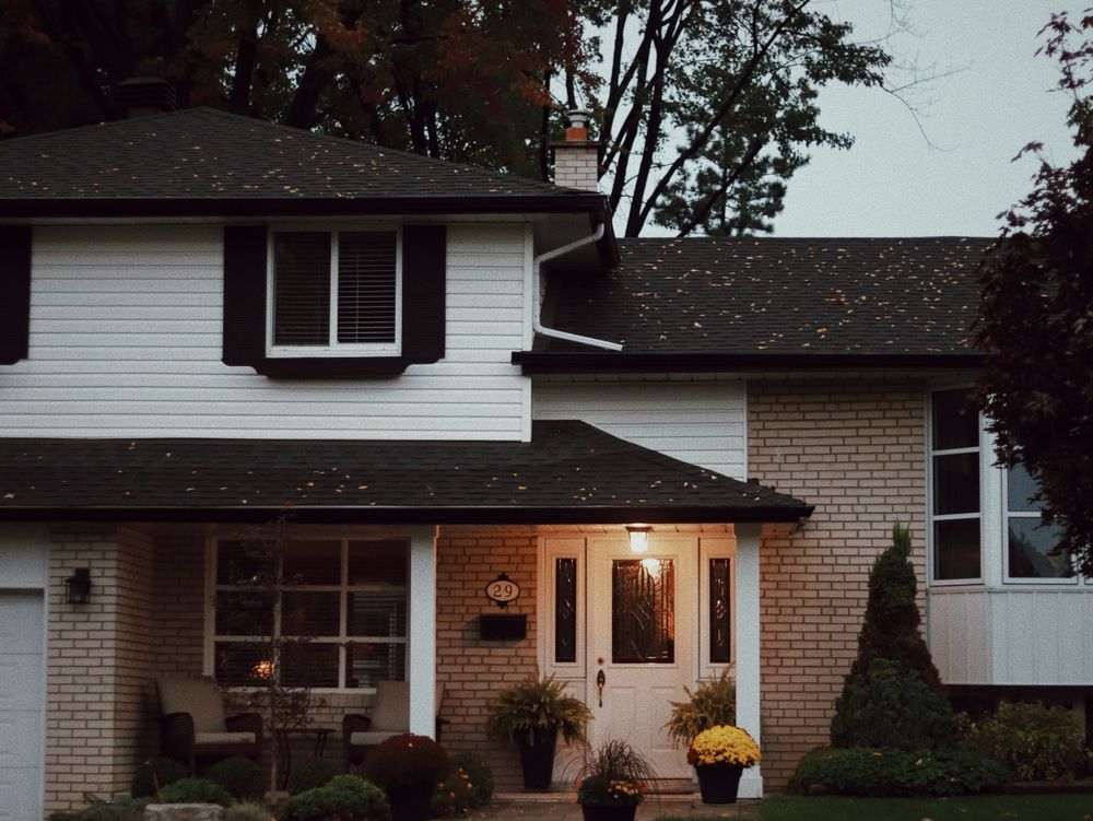 casa simples com fachada branca, telhado aparente e porta de madeira branca com vidro