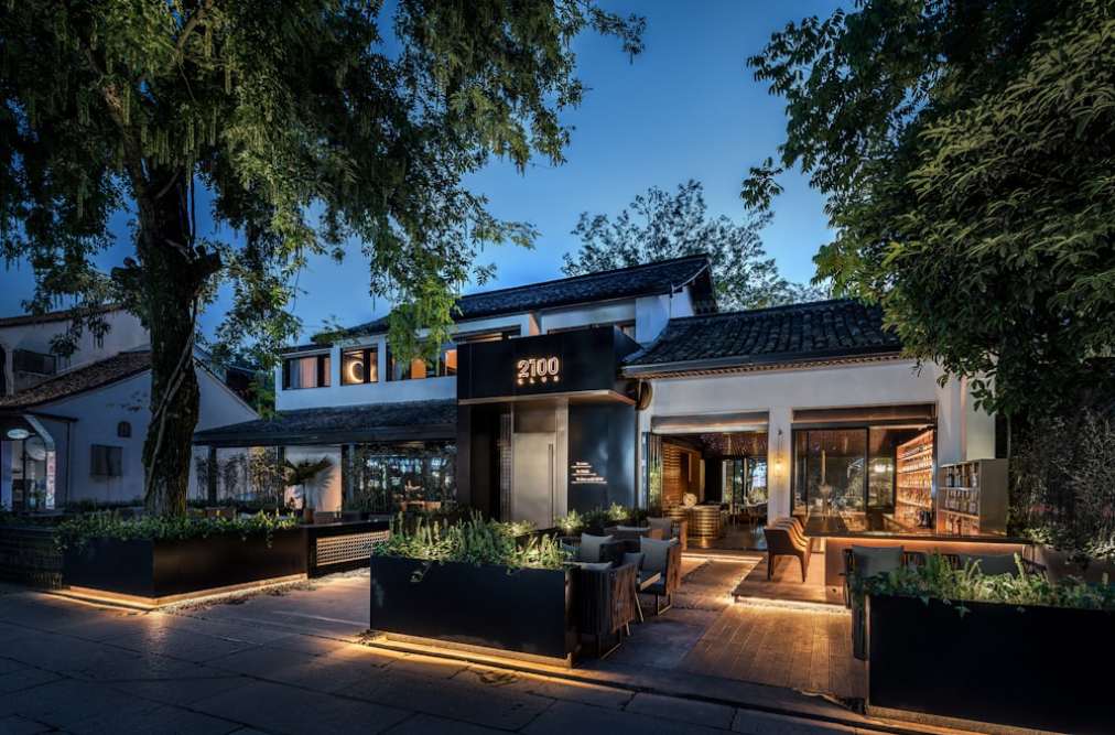 Fachada de casa moderna à noite, iluminada por luzes que destacam seus detalhes