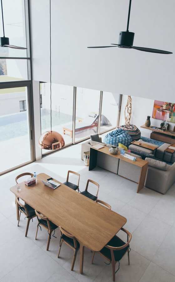 sala de estar com mesa de madeira, sofá cinza e puffs azul e colorido